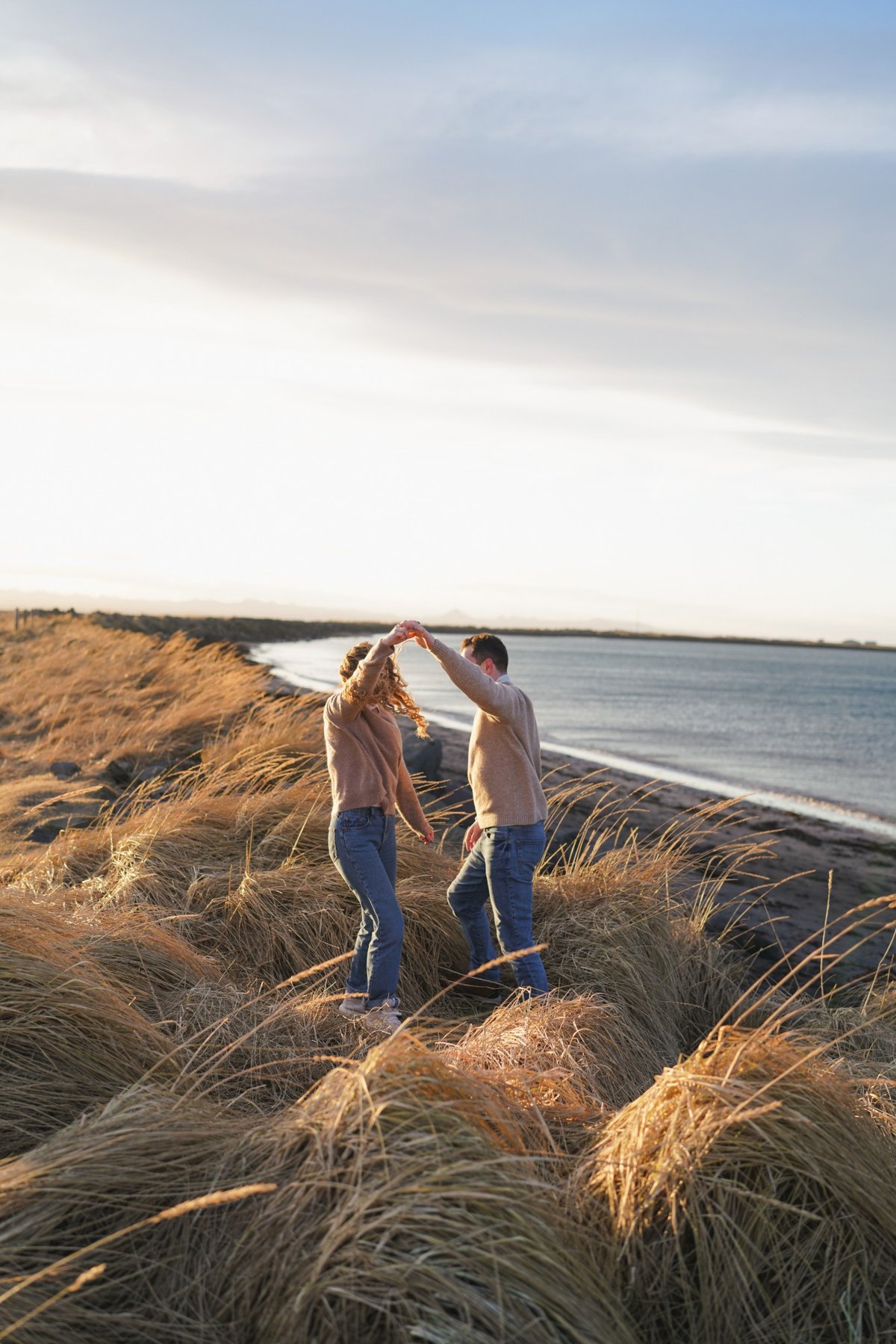 Austin twirling Ana in the dune grass by the water